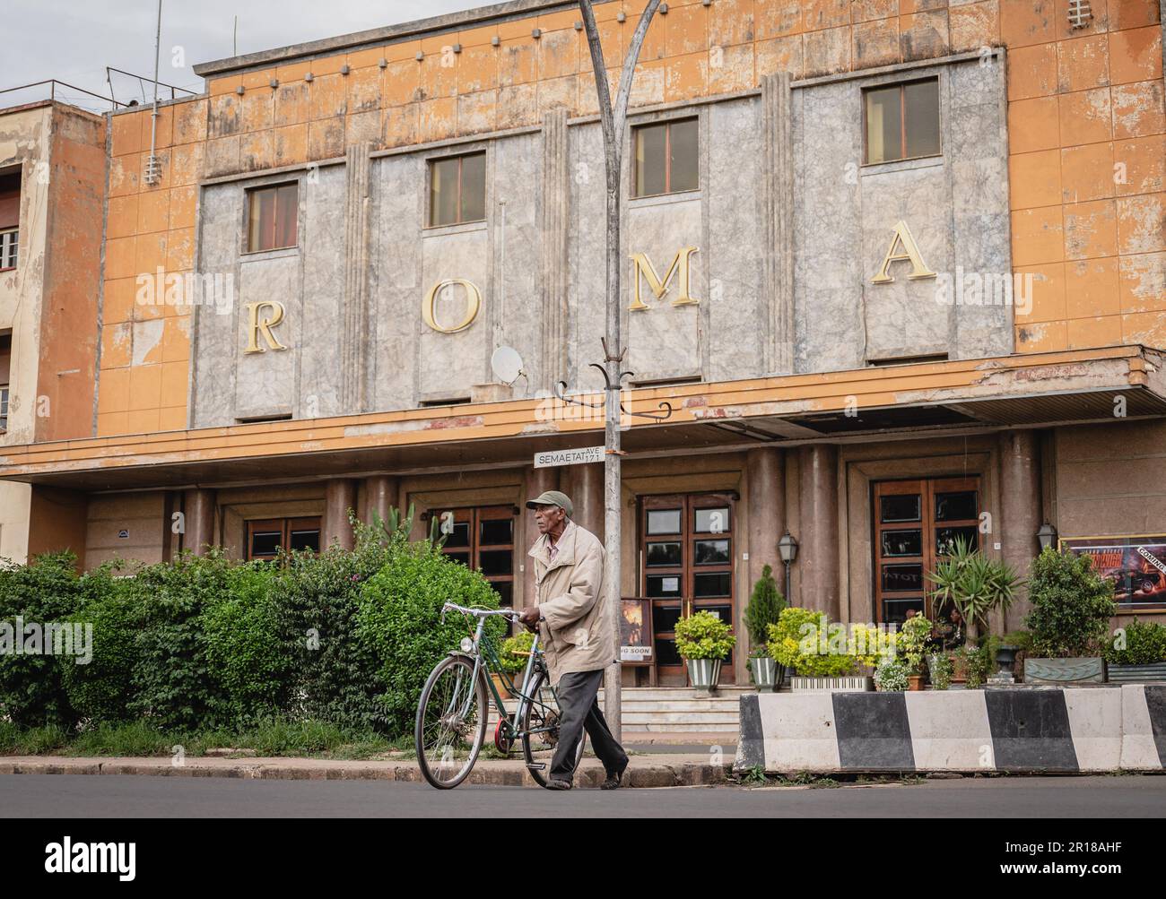 Asmara, Eritrea. 8. Mai 2023. Ein älterer schiebt sein Fahrrad vor das Wahrzeichen des Cinema Roma in Asmara, Eritrea, am 8. Mai 2023. Das Radfahren wurde in das Leben der Einheimischen integriert und wurde zu einem wichtigen Sport in Eritrea. Kredit: Wang Guansen/Xinhua/Alamy Live News Stockfoto