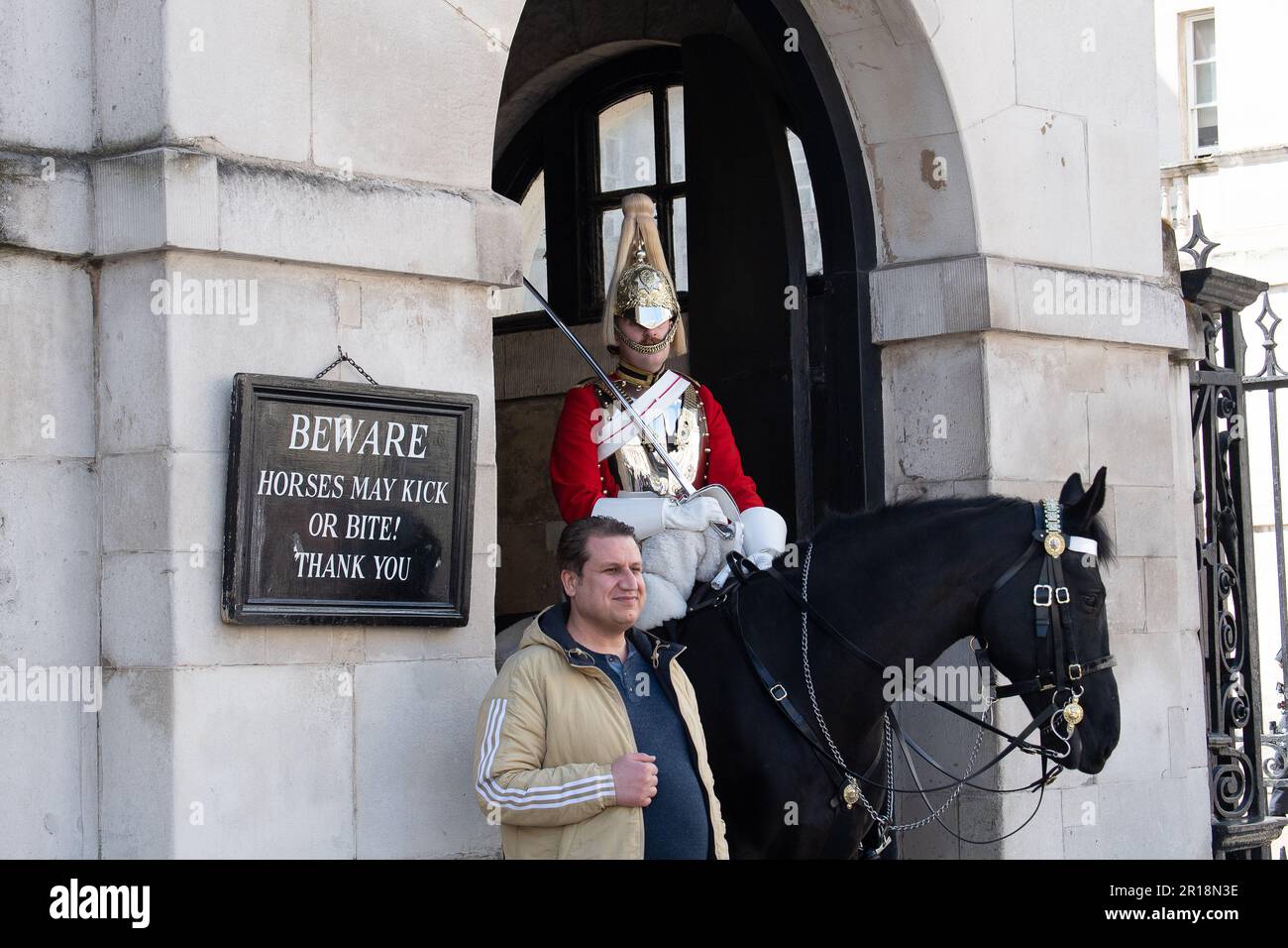 Whitehall, London, Großbritannien. 28. April 2023. Ein King's Life Guard setzte zwei montierte Wachen auf der Horse Guard's Parade in Whitehall ein. Trotz klarer Schilder, die Besucher und Touristen darauf hinweisen, dass die Pferde treten oder beißen können, bestehen Touristen immer noch darauf, direkt neben den Pferden zu stehen und zu bewachen. Es gab in letzter Zeit mehrere Male, dass ein Wachmann einen Touristen rufen musste, um zurückzukommen. Kredit: Maureen McLean/Alamy Stockfoto