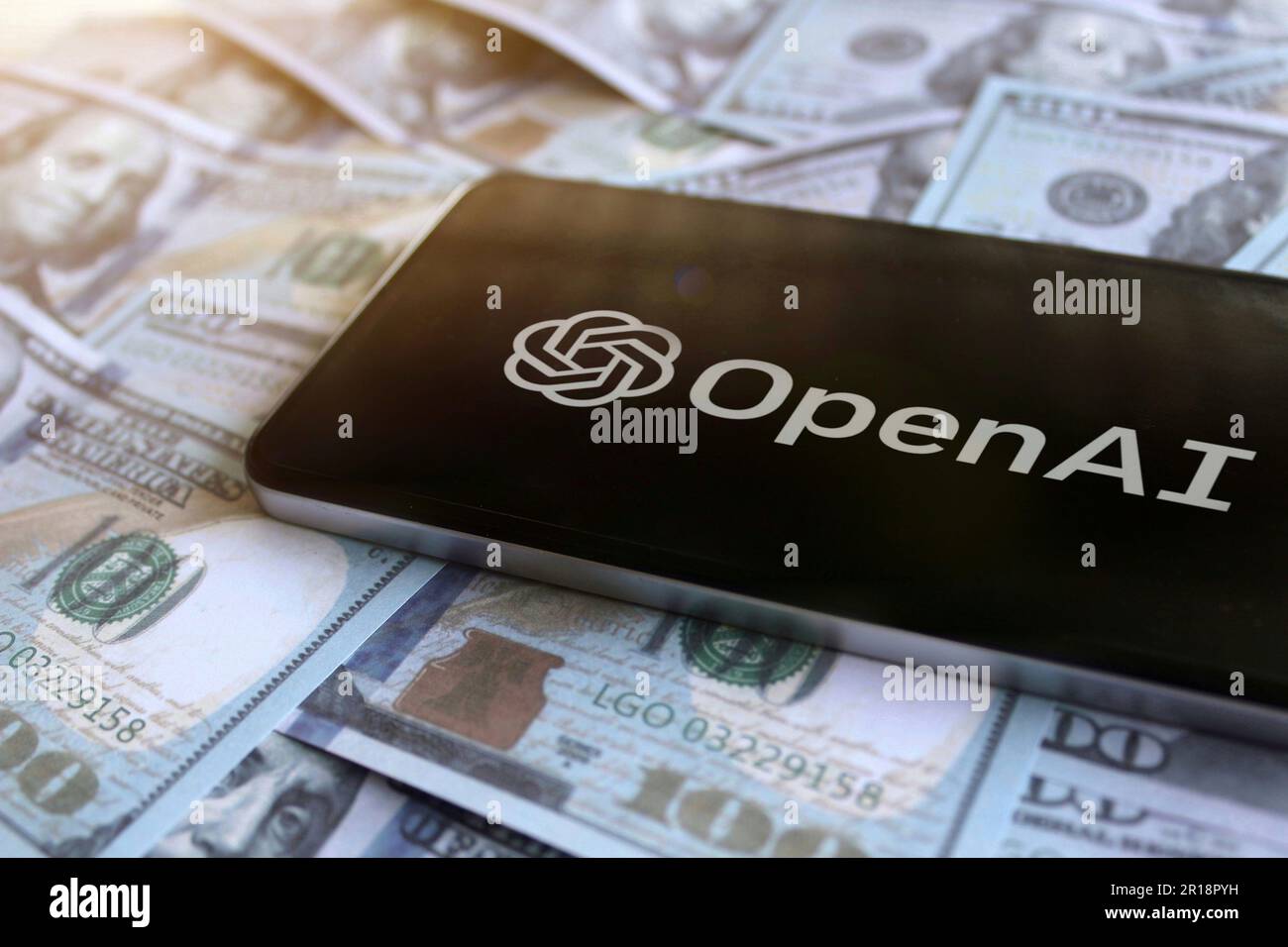 OpenAI-Logo auf dem Smartphone auf dem Geldhaufen. Stockfoto