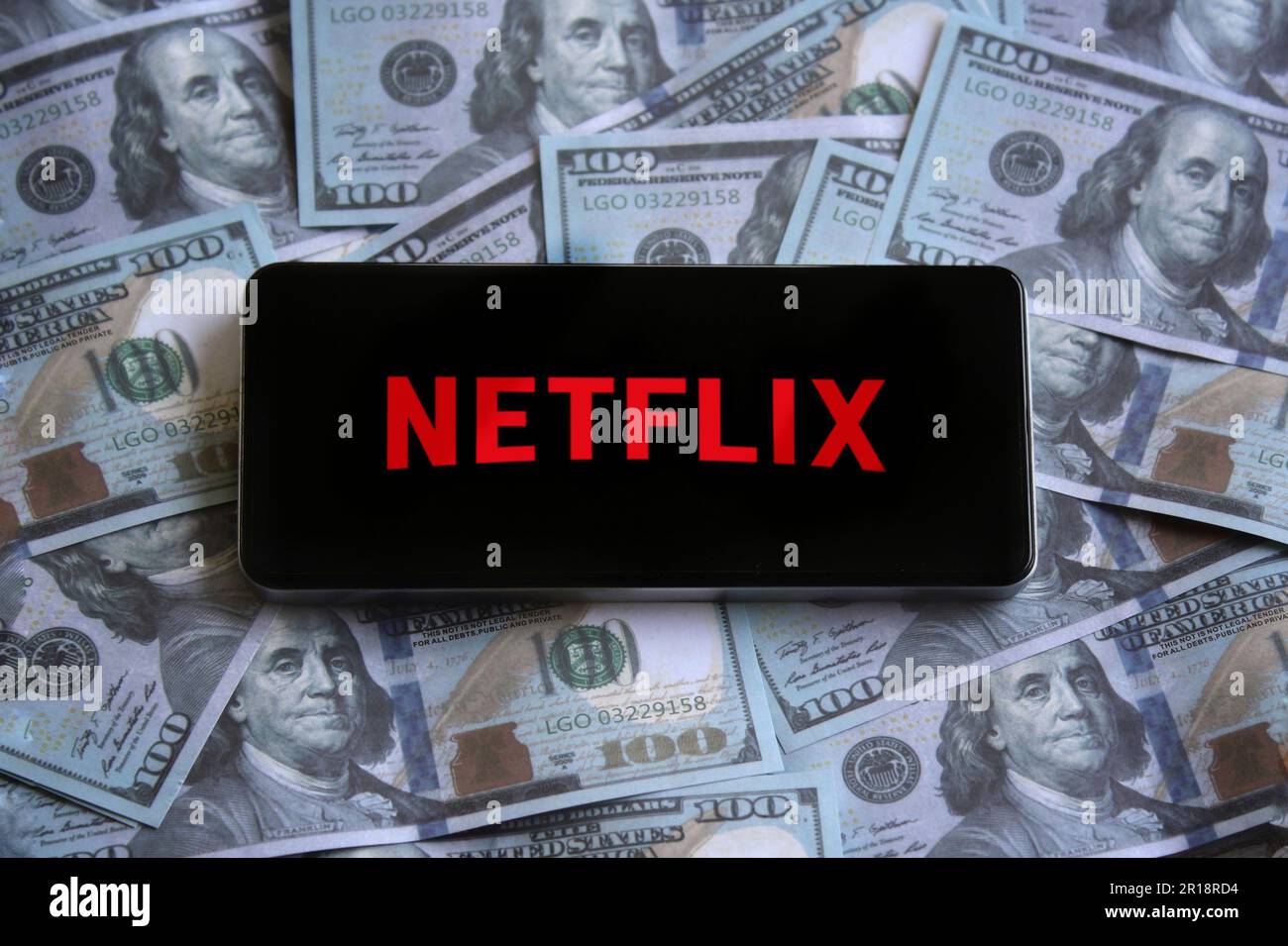 Das Netflix-Logo wird auf dem Smartphone auf dem Geldhaufen angezeigt. Stockfoto