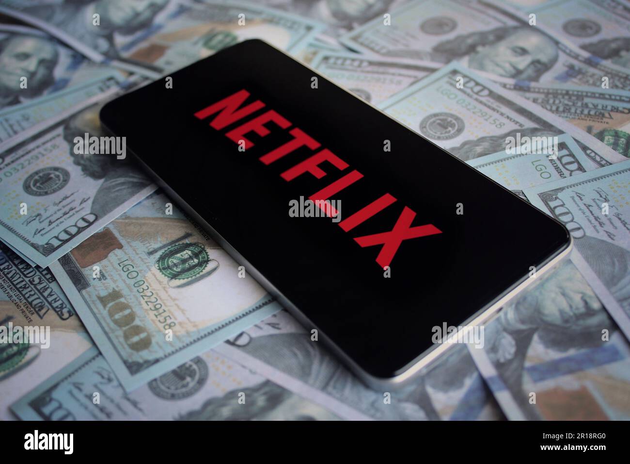 Das Netflix-Logo wird auf dem Smartphone auf dem Geldhaufen angezeigt. Stockfoto
