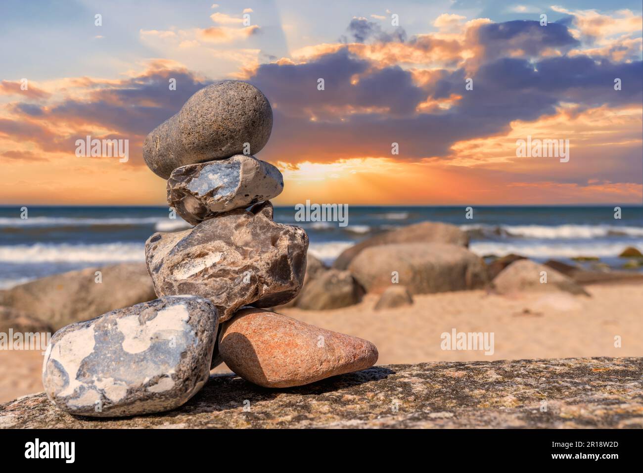 Steinpyramiden und Glaskugel am traumhaften Ostsee-Sandstrand auf Rügen zum spektakulären orange Sonnenuntergang Stockfoto