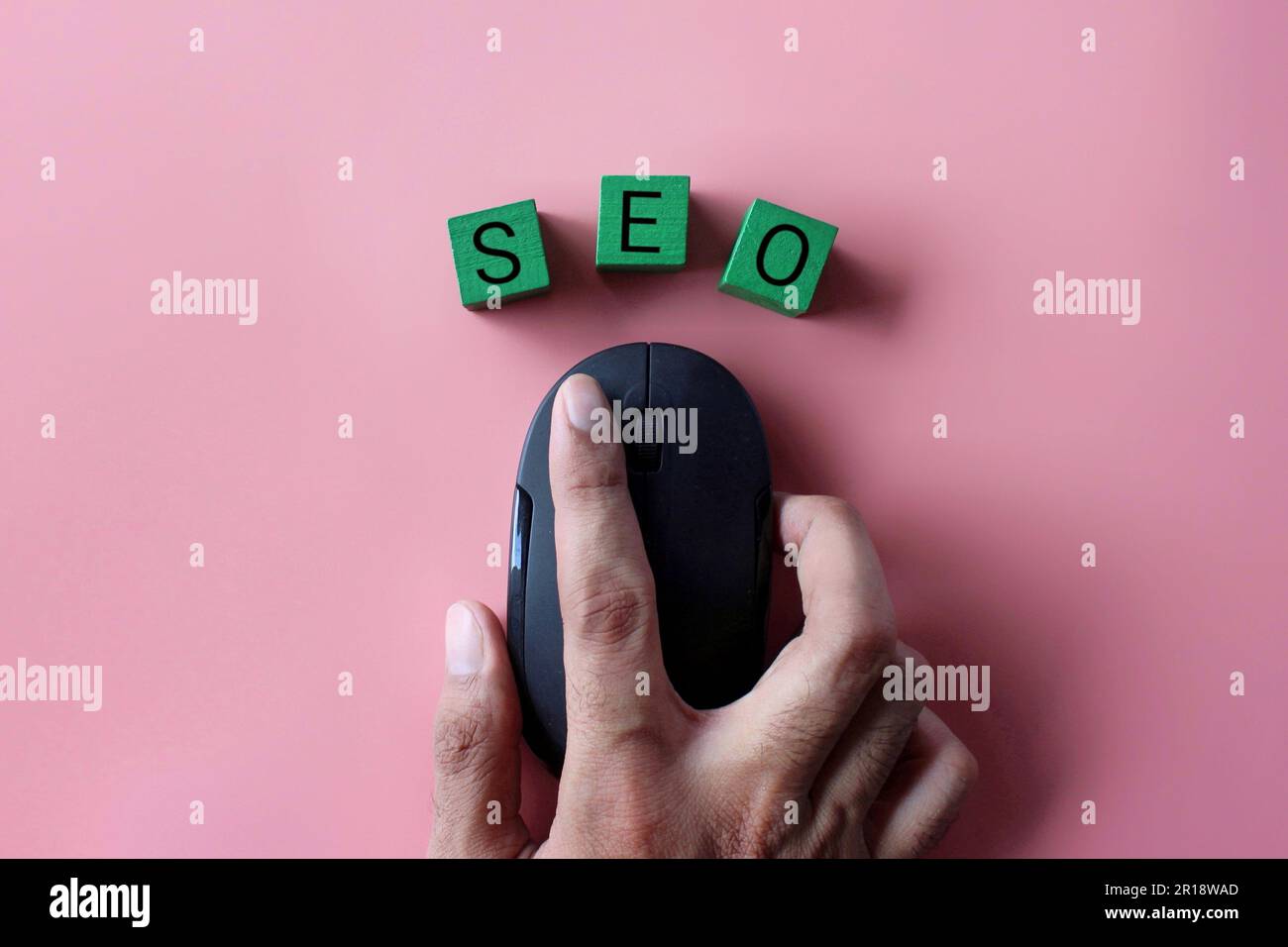 Hand-Klick-Computermaus mit Text SEO auf pinkfarbenem Hintergrund. Konzept der Suchmaschinenoptimierung. Stockfoto