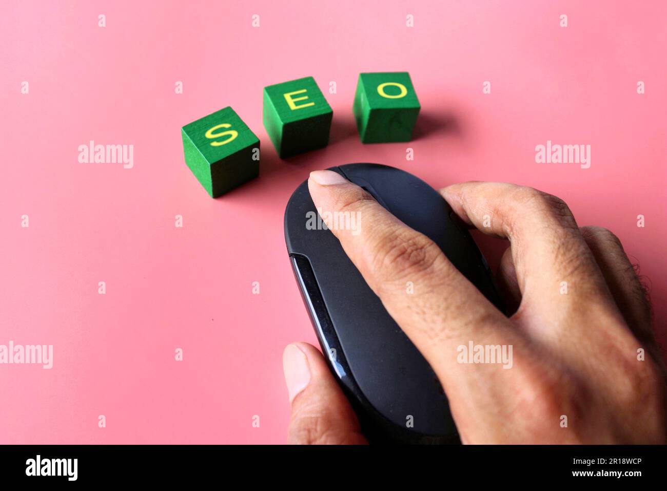 Hand-Klick-Computermaus mit Text SEO auf pinkfarbenem Hintergrund. Konzept der Suchmaschinenoptimierung. Stockfoto