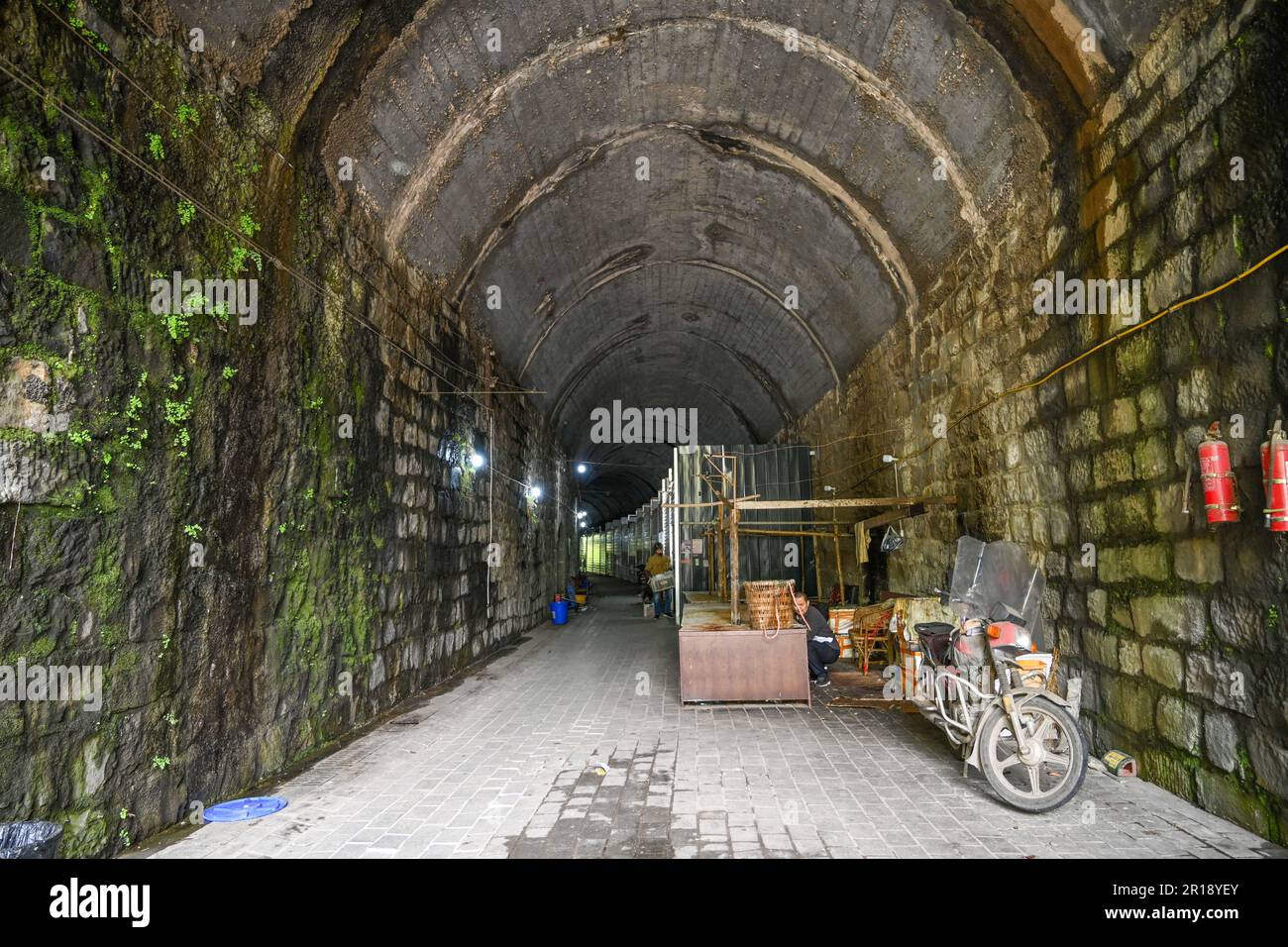 CHONGQING, CHINA - 8. MAI 2023 - das am 8. Mai 2023 aufgenommene Video zeigt einen Lebensmittelmarkt in einem verlassenen Eisenbahntunnel in Chongqing, China. In diesem hundert Meter langen Tunnel sind mehr als 20 Stände nacheinander angeordnet. Die Verkaufsstände sind in feste Verkaufsstände und provisorische Verkaufsstände unterteilt, und die festen Verkaufsstände sind in Fleischbereiche und Bereiche für Wasserprodukte unterteilt. Es wird davon ausgegangen, dass der Tunnel Teil der ehemaligen Eisenbahnlinie des Spezialstahlwerks Chongqing ist, die eine Tunnellänge von etwa 150 Metern hat. Nach dem Bankrott des Spezialstahlwerks Chongqing wurden die einst befahrenen Tunnel allmählich still, A Stockfoto