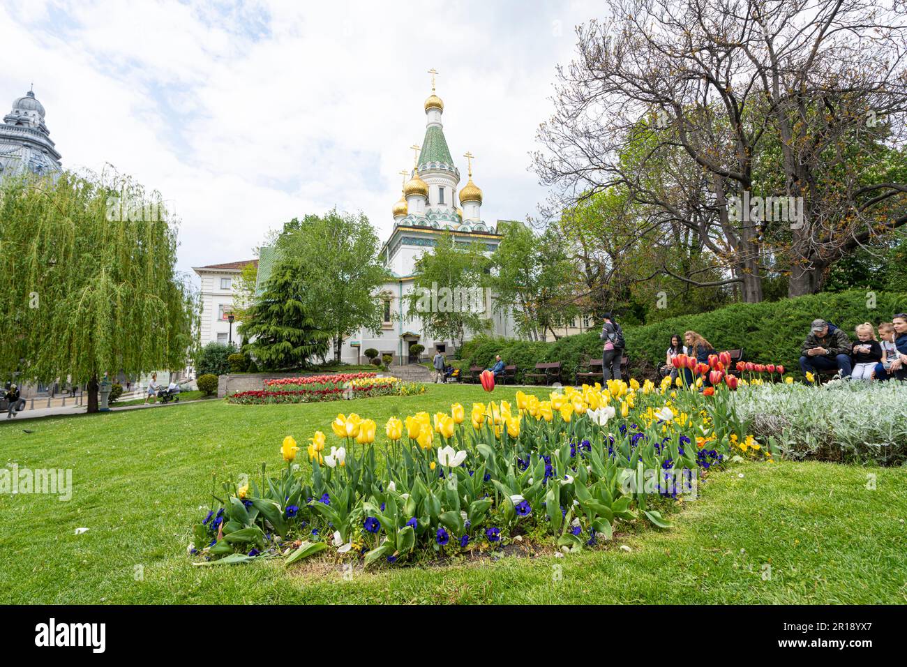 Sofia, Bulgarien. Mai 2023. Tulpen im russischen Kirchengarten mit den Kuppeln von St. Nicholas Kirche im Hintergrund Stockfoto