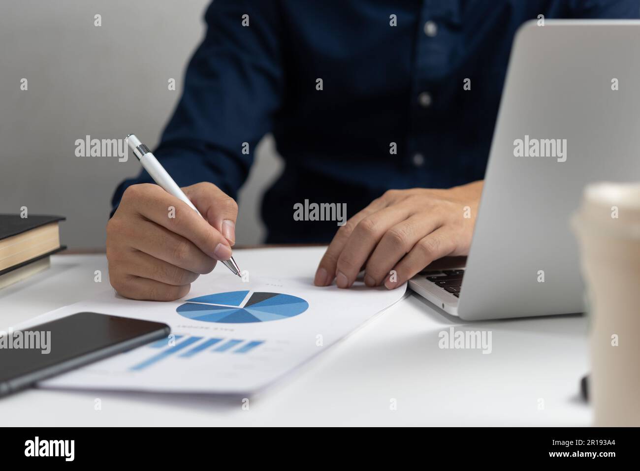 Geschäftsmann, der ein Stiftdokument und ein Diagramm hält, hält Buchhaltungsmarketing mit einem Computer-Laptop. Stockfoto