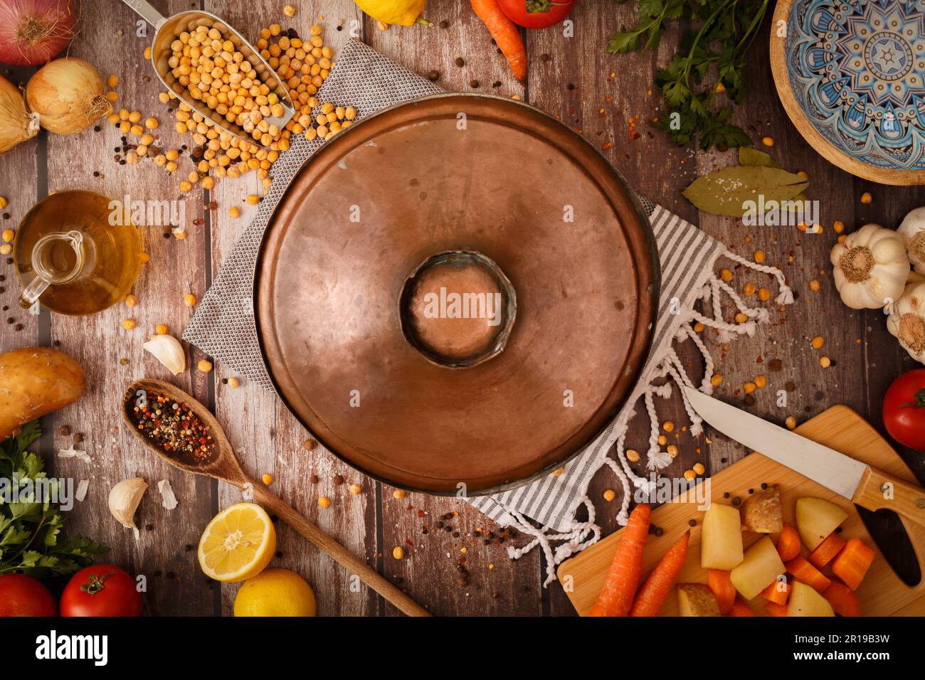 Verschiedene Bio-Gemüse Zutaten rund um die Zeit Bronze Kochtopf auf rustikalem Holztisch, Holzlöffel und -Schüsseln. Speicherplatz kopieren. Draufsicht. Bio ve Stockfoto