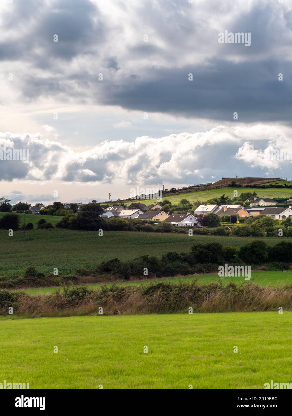 Himmel mit Kumuluswolken über einem kleinen irischen Dorf an einem Sommerabend. Irische Siedlung im County Cork, dramatische Landschaft. Europäisches Land, rus Stockfoto