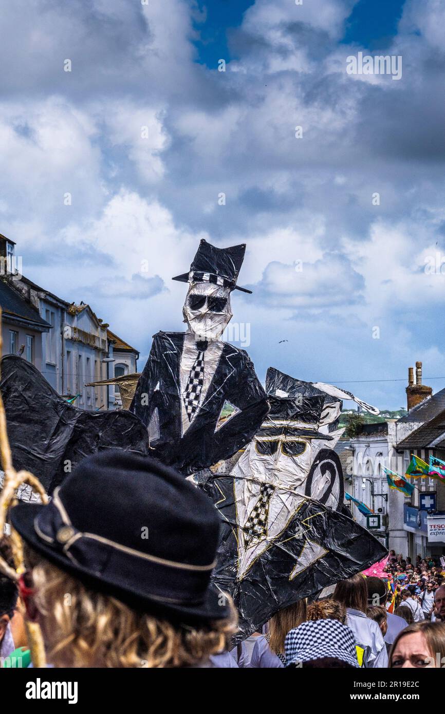 Leute, die große mit- und Papierfiguren von unhöflichen zwei-Ton-Figuren bei der Mazey-Day-Parade beim Golowan Festival in Penzance in Cornwall i dabei hatten Stockfoto