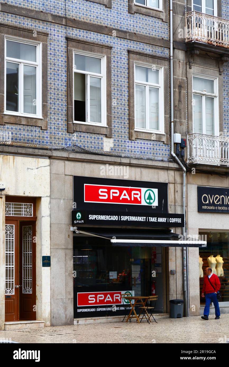 Mann, der am Spar-Supermarkt-Gebäude auf Praca de Carlos Alberto, Porto/Porto, Portugal vorbeigeht Stockfoto