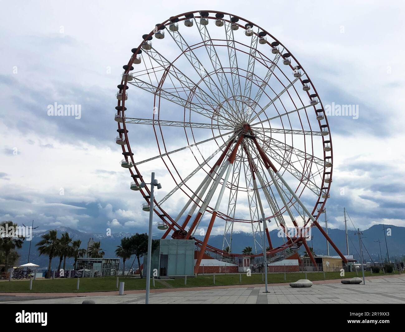Ein großes rundes, wunderschönes Riesenrad, eine Panoramaplattform in einem Park in einem tropischen, warmen Sommerresort mit Palmen vor blauem Himmel. Stockfoto
