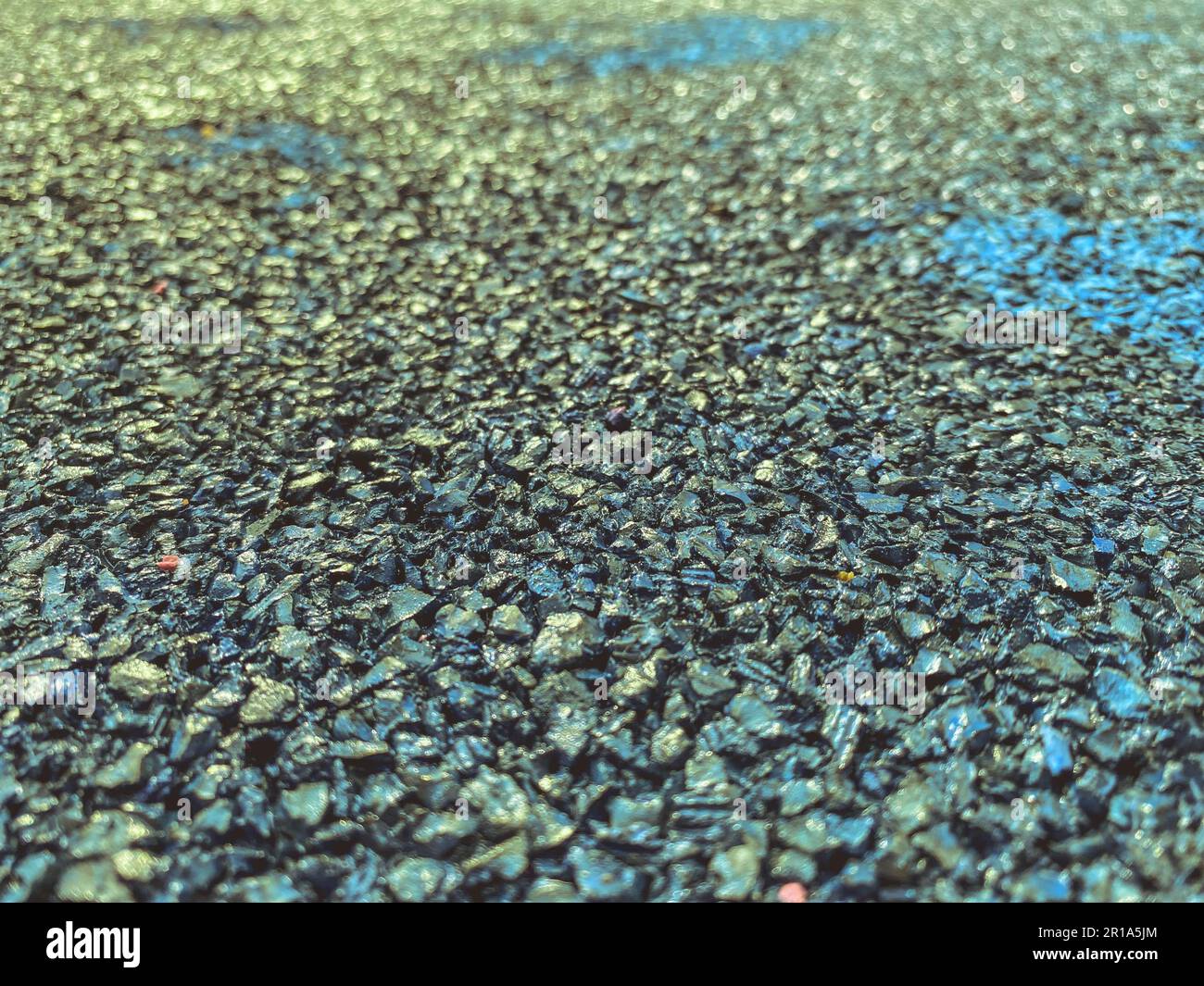 Graue Textur, Steine verschiedener Farben. Ein Hintergrund aus kleinen schwarzen, scharfen Steinen, die fest auf der Straße verstaut sind. Abdeckung für Sportplatz. Stockfoto