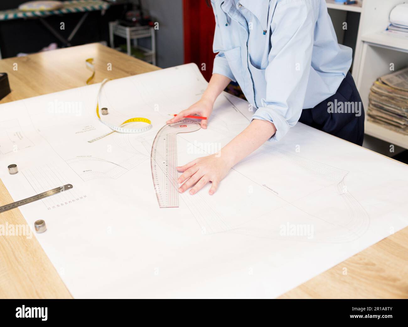 Die Designer-Schneiderin nimmt präzise Messungen für Nähkleidung vor. Das Konzept der Kleiderherstellung. Stockfoto