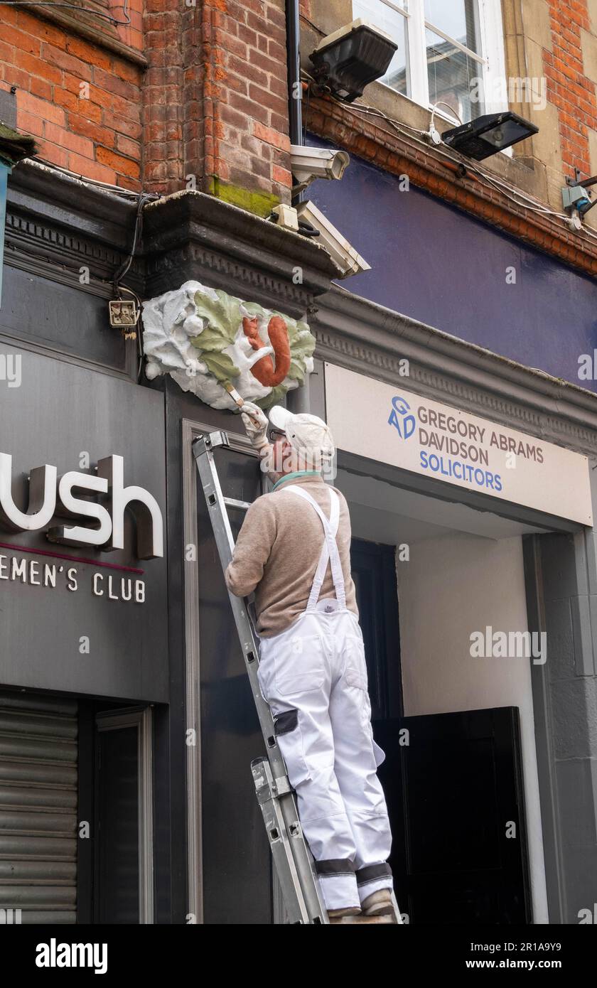 Maler auf der Leiter malt Bas-Relief vor dem Mathew Street Club in Liverpool neu Stockfoto