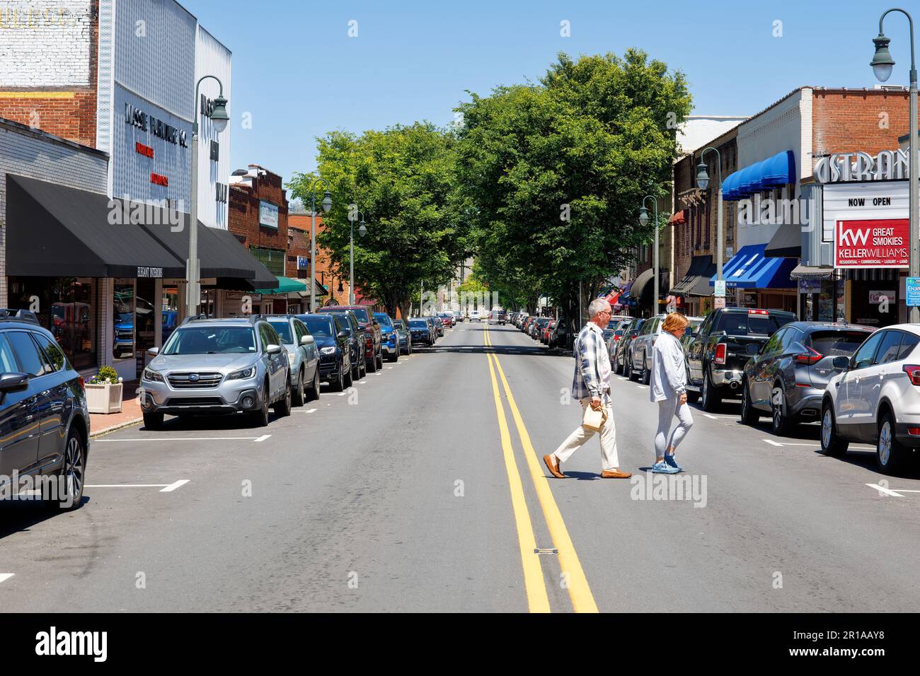 WAYNESVILLE, NC, USA-4. MAI 2023: Ehepaar überquert die Main Street am sonnigen Sommertag. Blick auf die Straße. Stockfoto