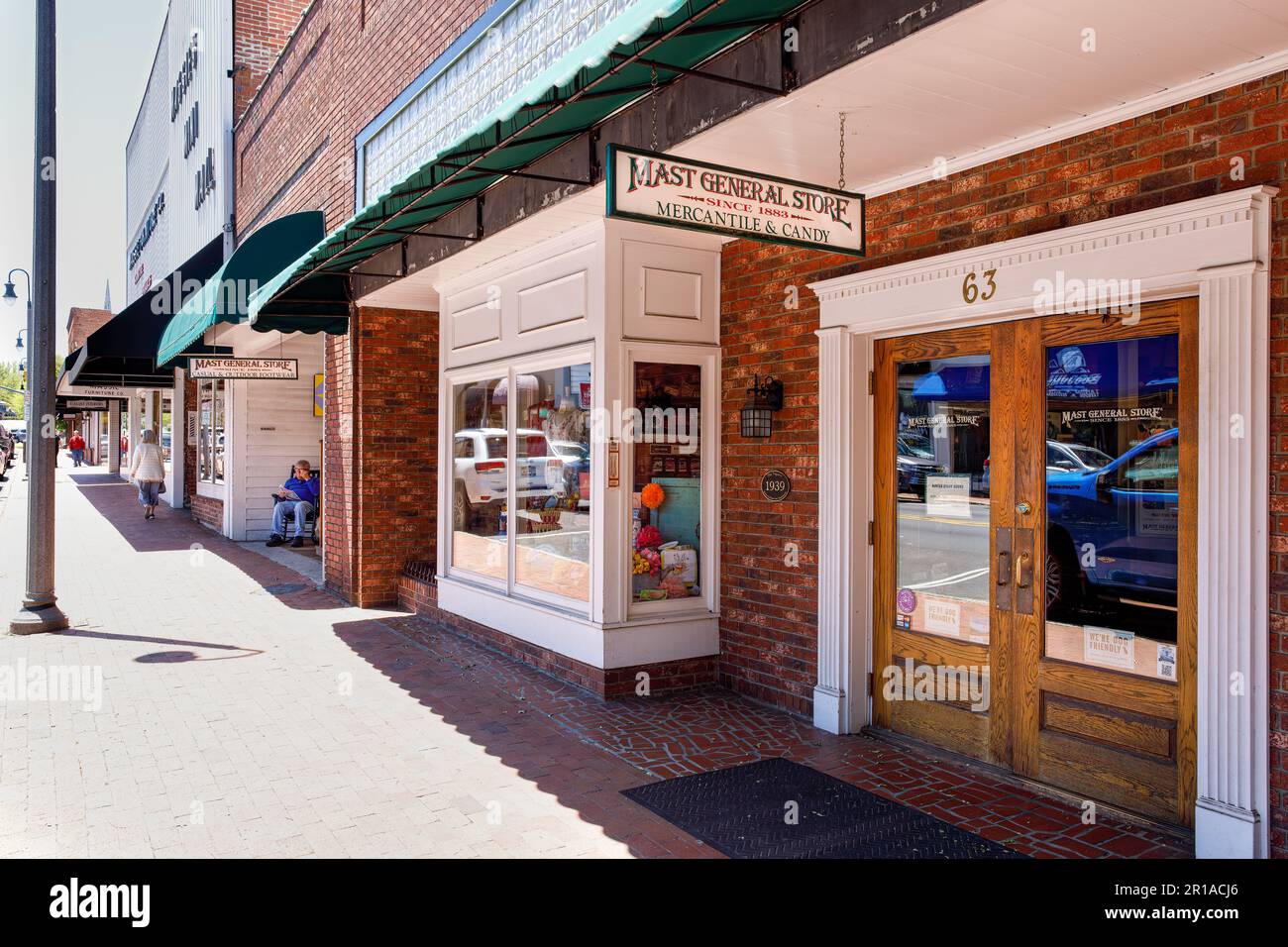 WAYNESVILLE, NC, USA-4. MAI 2023: Blick auf den Bürgersteig mit den Eingängen des Mast General Store, Mann im Stuhl, Frau im Gehen. Stockfoto