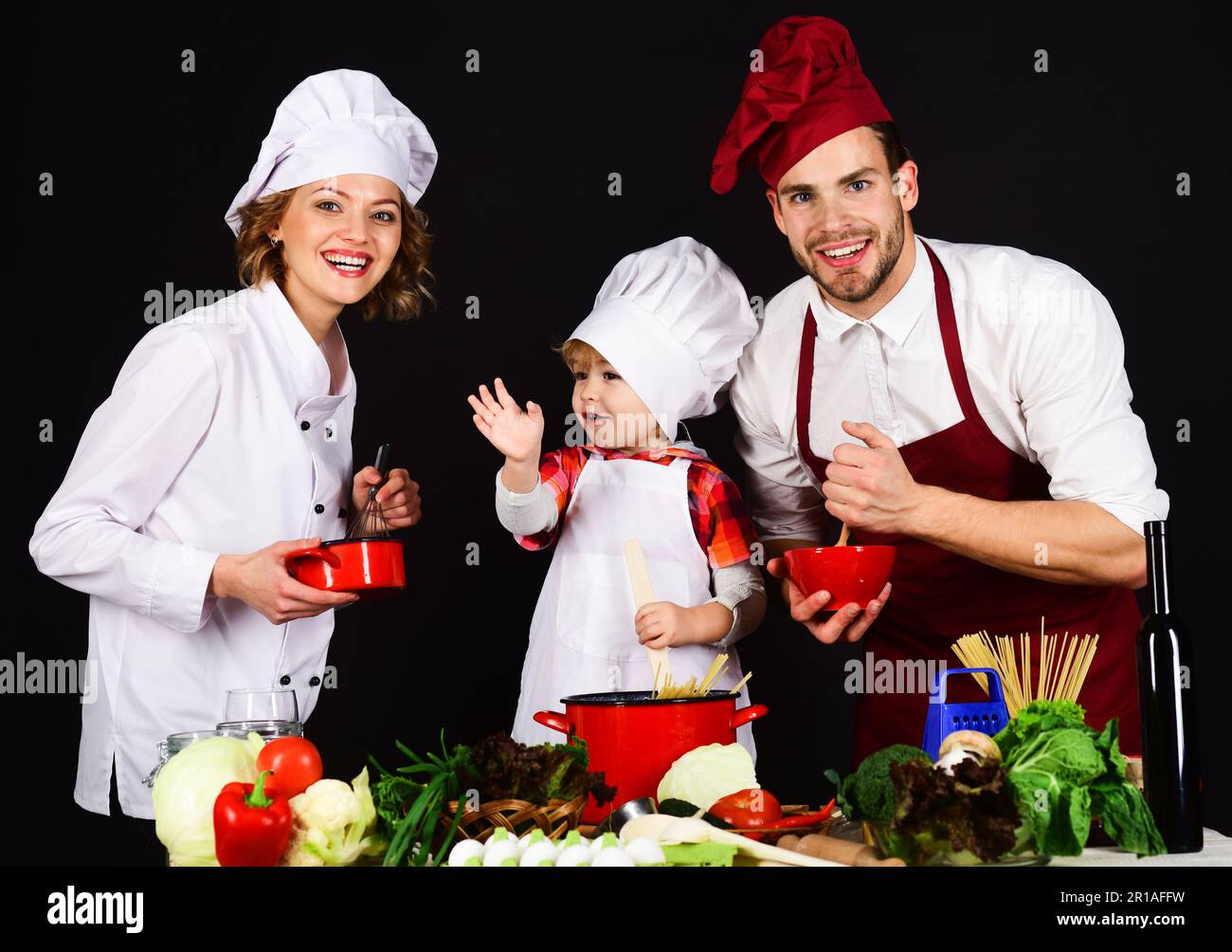 Mutter, Vater und Sohn bereiten Frühstück oder Abendessen in der Küche zu. Eltern, die dem Jungen das Kochen beibringen. Fröhliche Familienkochen zu Hause. Hausgemacht und Stockfoto