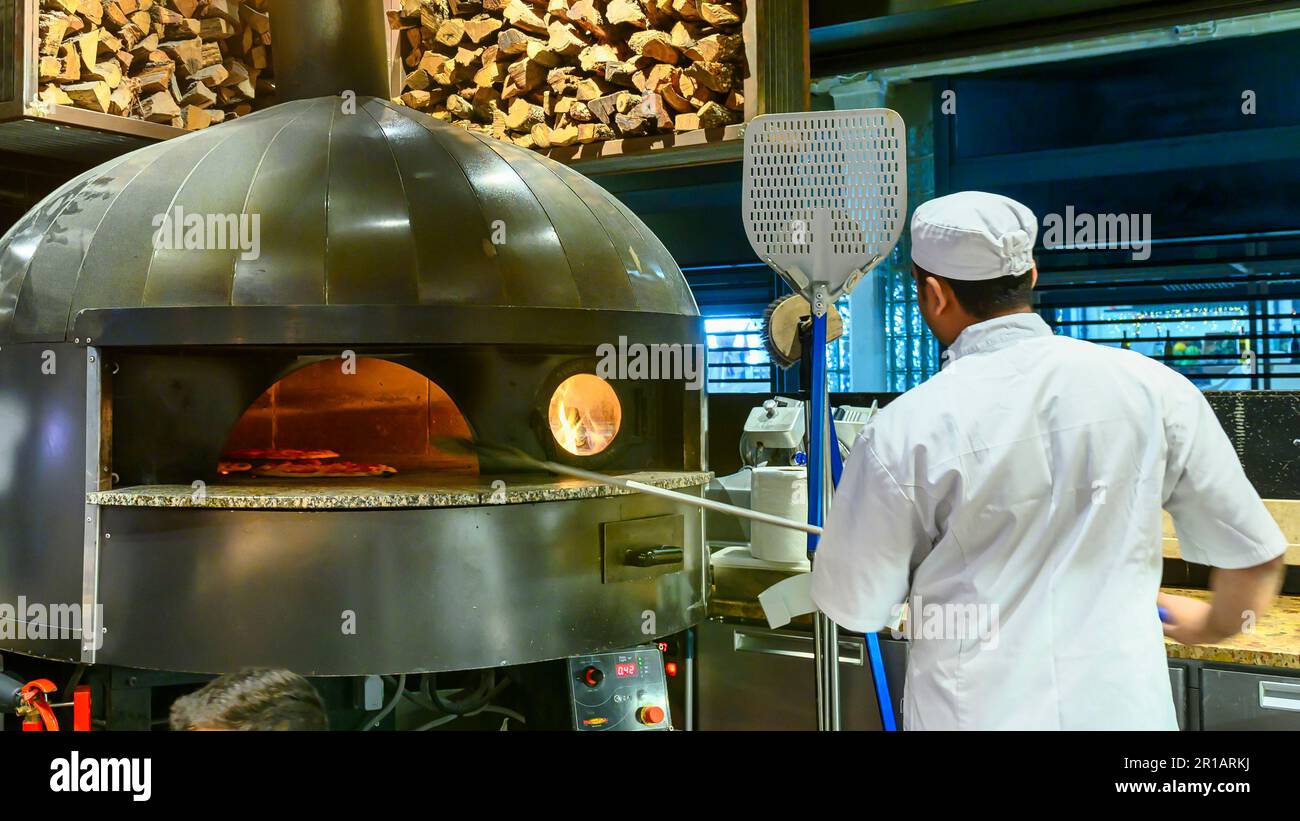 Ein Mann, der eine Pizza in einem Holzofen kocht. Auch bekannt als Ribeira-Markt, ist der berühmte Ort eine Sehenswürdigkeit in der Stadt. Stockfoto