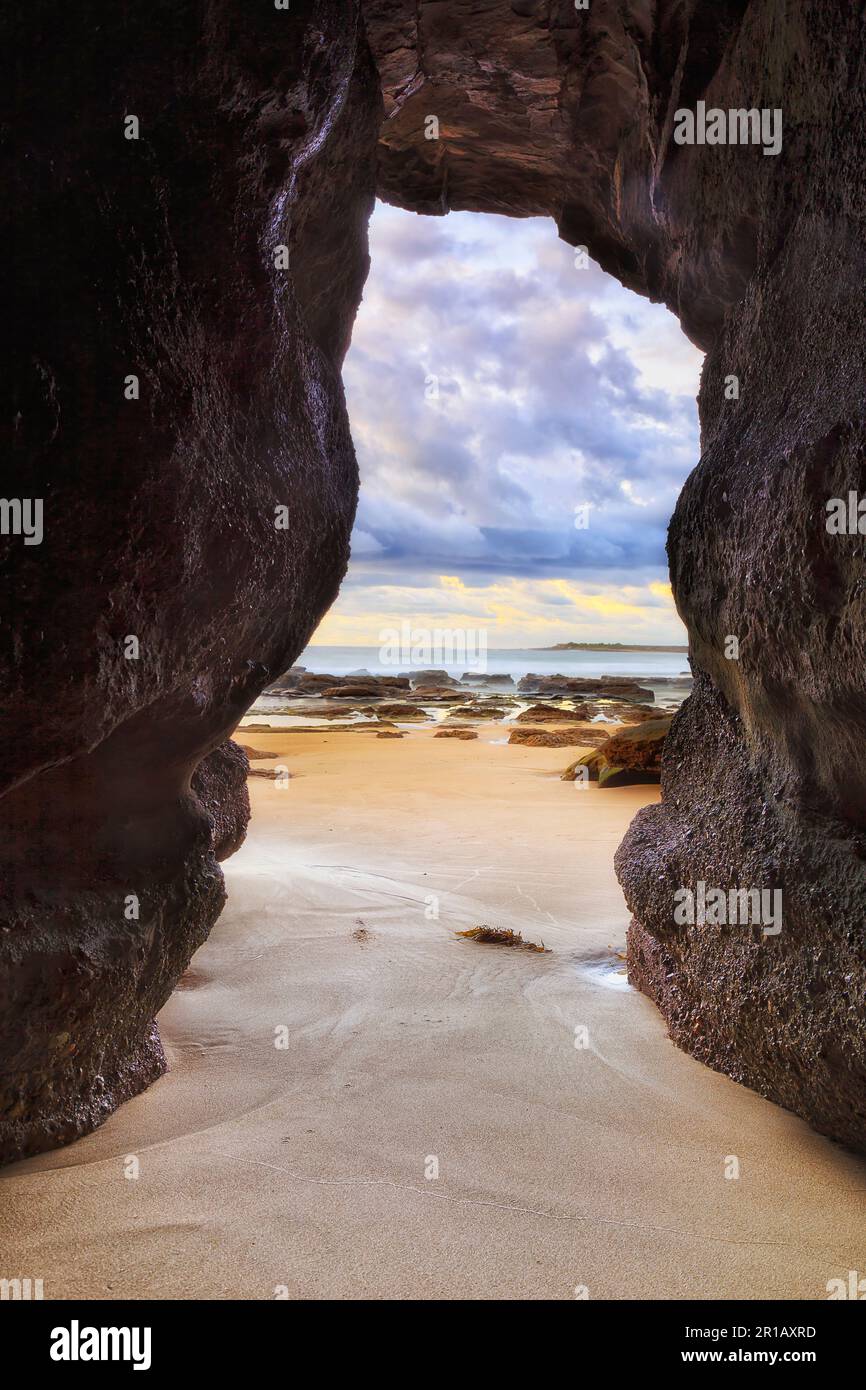 Malerische Sandsteinhöhle, die bei Sonnenaufgang in die Küstenstadt Caves Beach an der Pazifikküste Australiens eindringt. Stockfoto