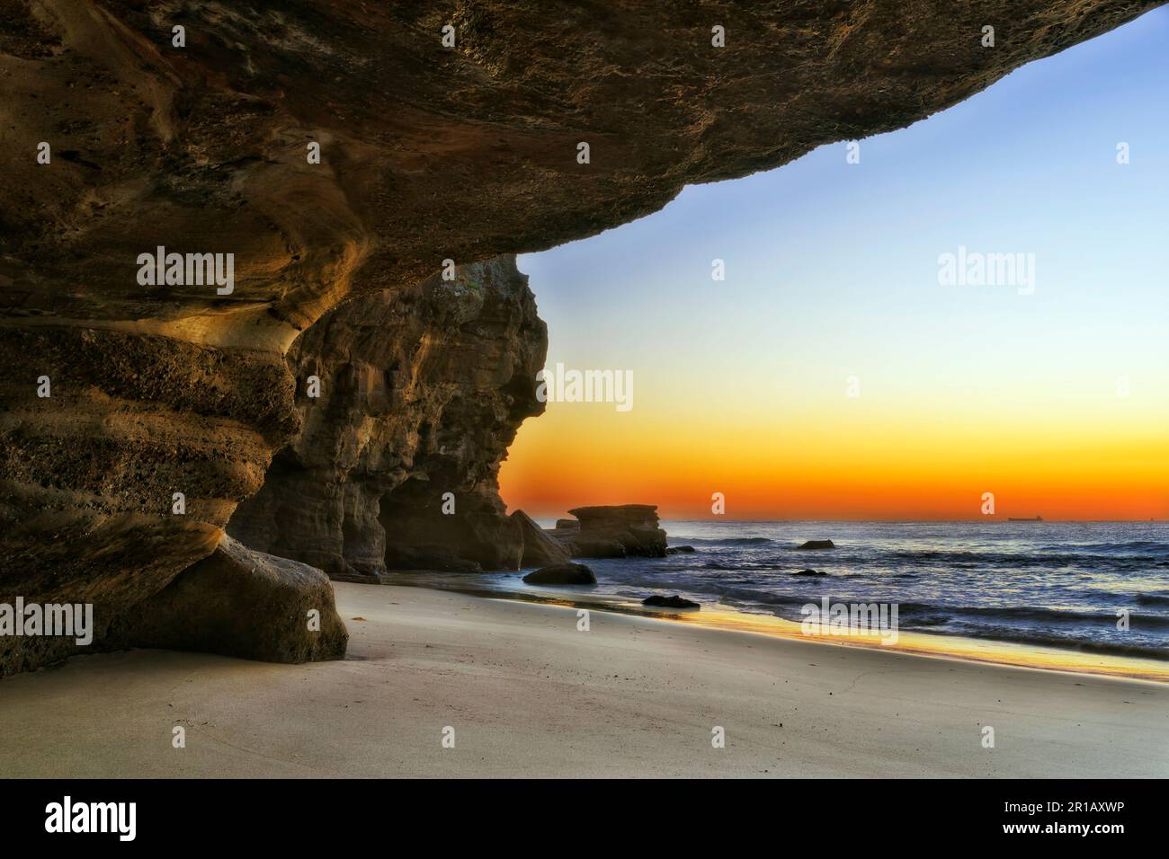 Sandsteinfelsen Meereshöhle am Caves Beach Pazifikküste Australiens bei Sonnenaufgang - malerische Meereslandschaft. Stockfoto