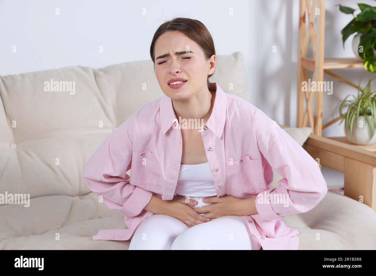 Junge Frau mit Zystitis auf dem Sofa zu Hause Stockfoto