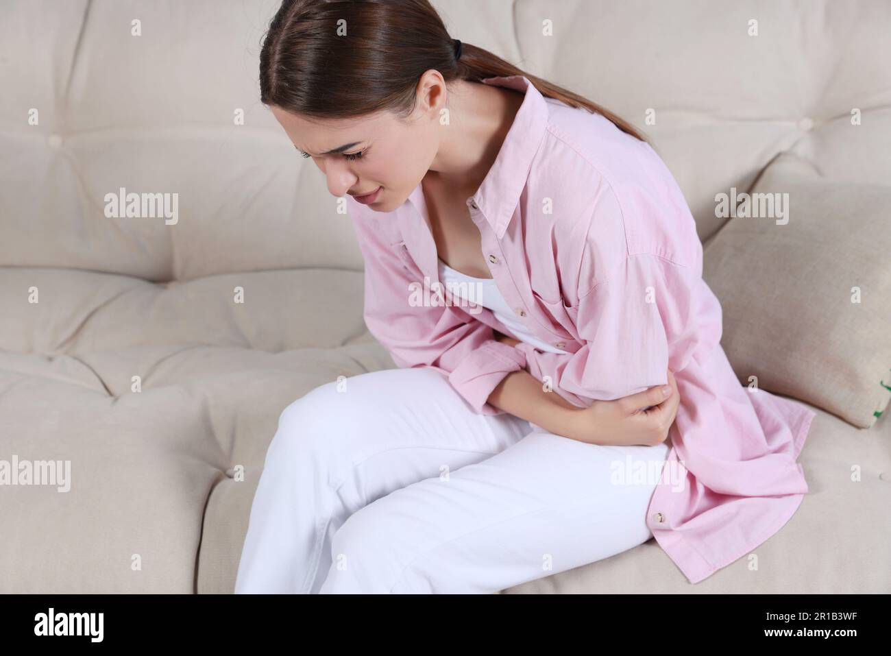 Junge Frau mit Zystitis auf dem Sofa zu Hause Stockfoto