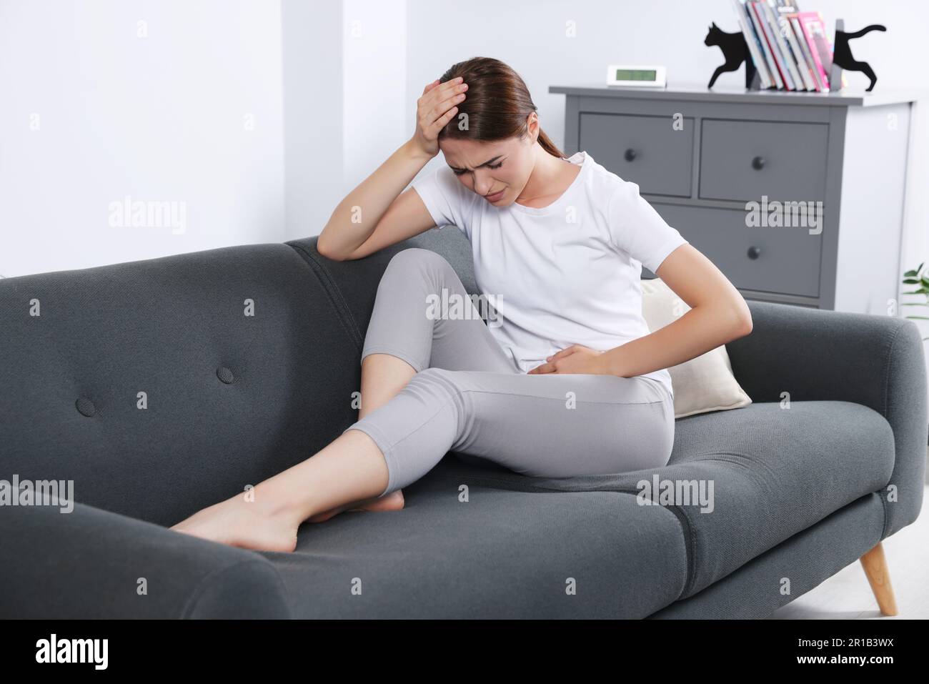 Junge Frau mit Zystitis auf dem Sofa zu Hause Stockfoto