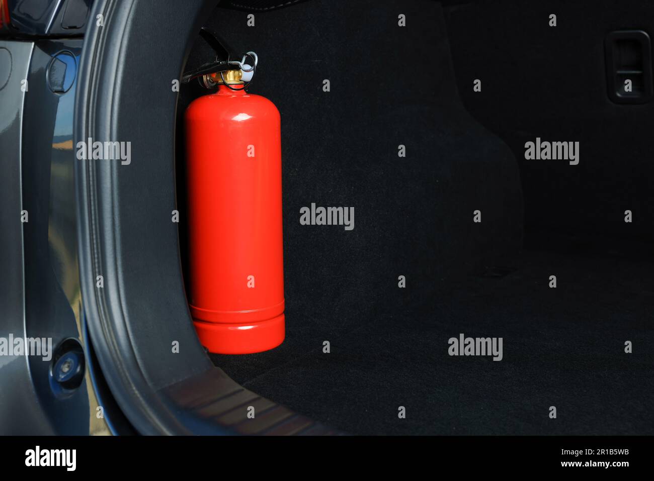 Roter Feuerlöscher im Kofferraum, Platz für Text. Sicherheitsausrüstung für Autos Stockfoto