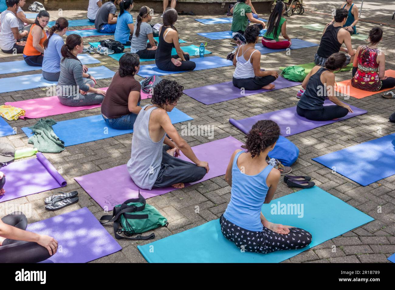 Männer und Frauen sitzen auf Polstern bei einem Yogakurs in einem Park in San José, Costa Rica. Stockfoto