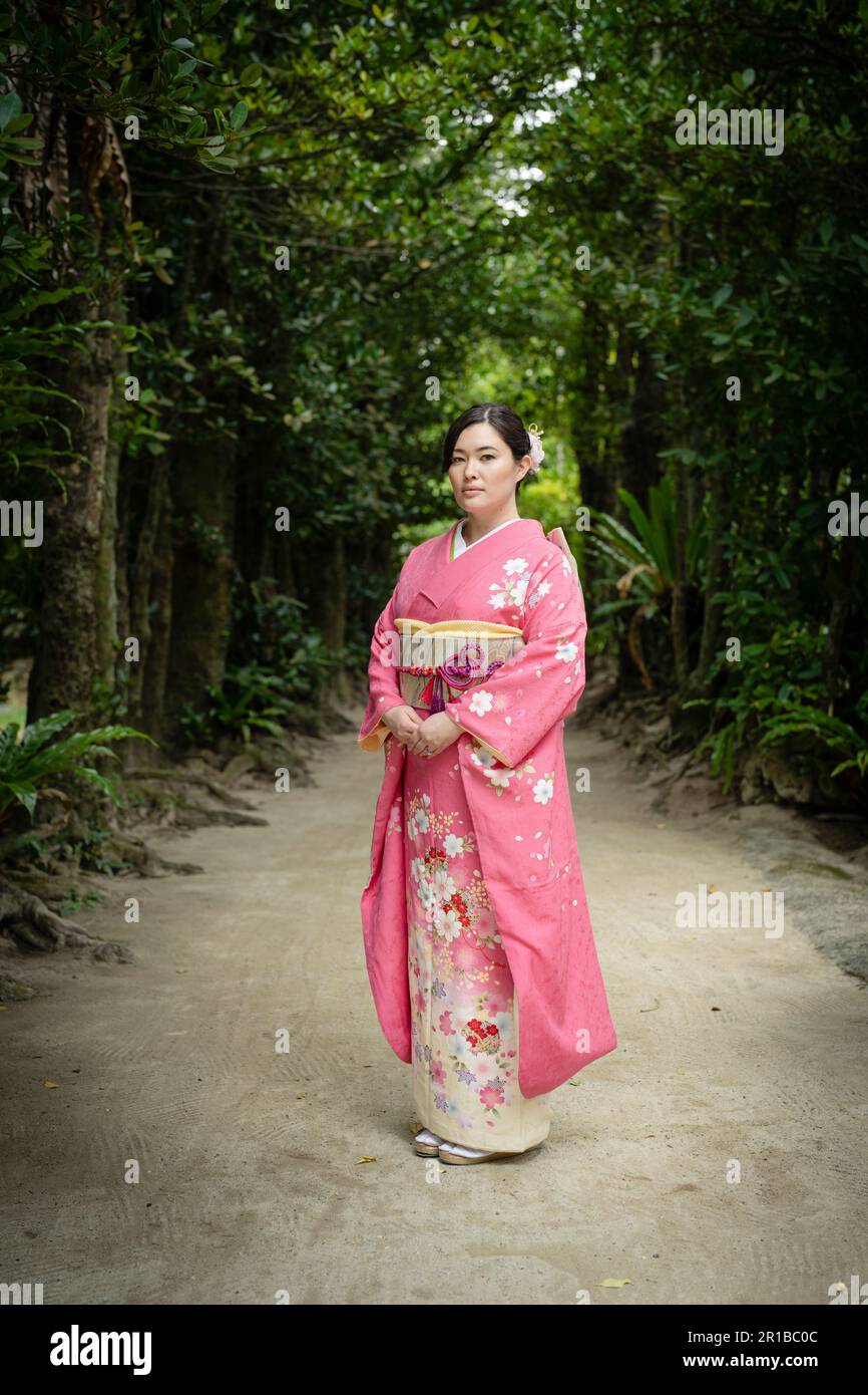 Wunderschöne junge, gemischte japanische/amerikanische Frau mit Kimono, die auf dem Fußweg von Bise Village, Motobu Town, Okinawa, Japan steht. Stockfoto