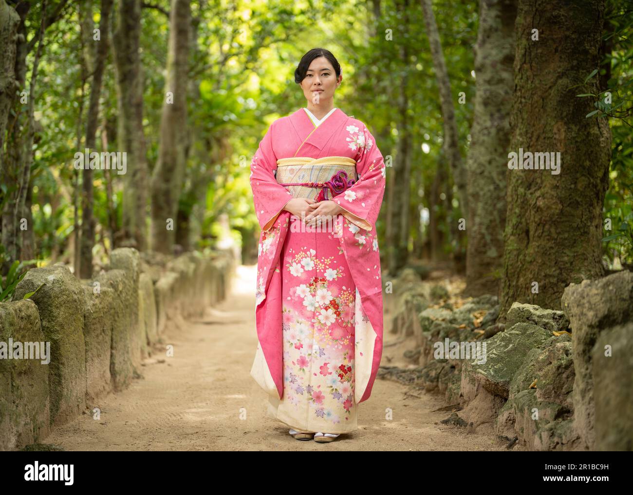 Wunderschöne junge, gemischte japanische/amerikanische Frau mit Kimono, die auf dem Fußweg von Bise Village, Motobu Town, Okinawa, Japan steht. Stockfoto