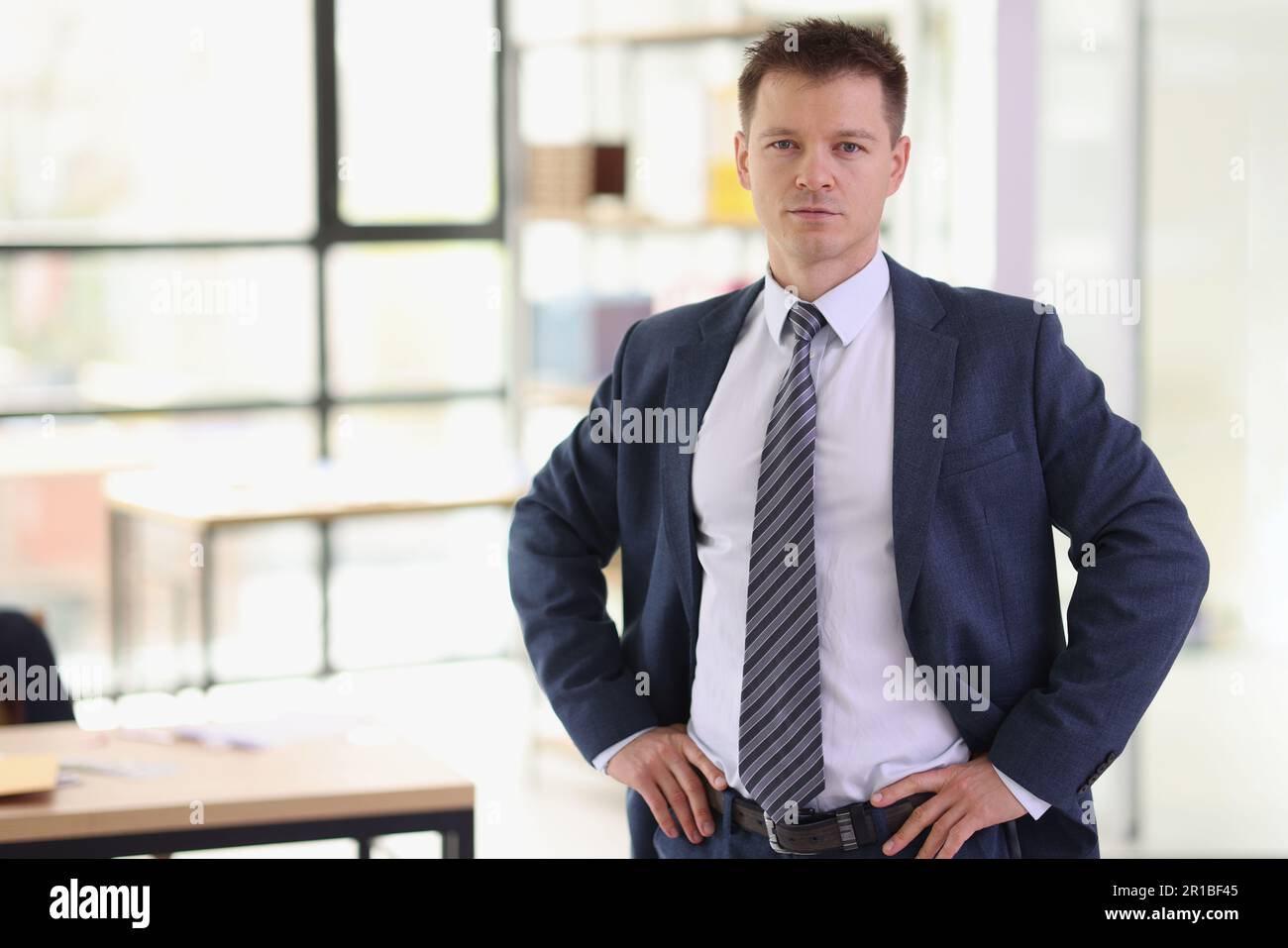 Ein seriöser Geschäftsmann hält sich im Amt an den Hüften fest Stockfoto