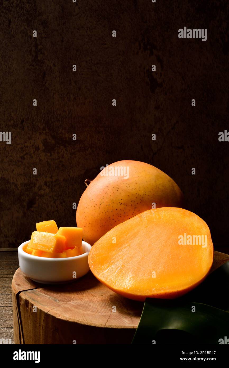 Mango- und Mangoscheiben mit Würfeln auf schwarzem Hintergrund. Thailändische Mangos. Thailändische Früchte. Text kopieren. Platz kopieren. Stockfoto