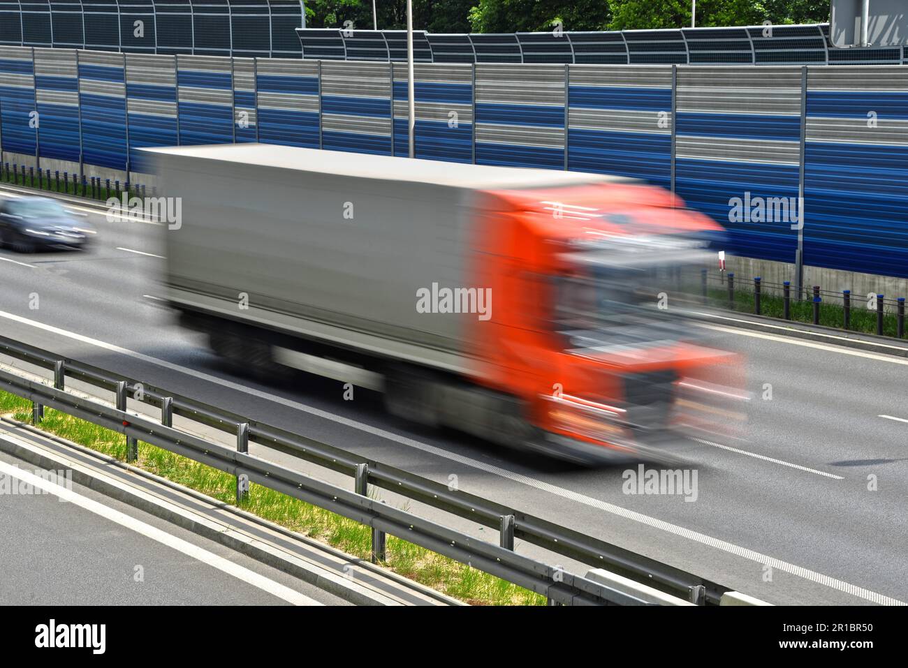 Großes Lastkraftwagen, das sich mit voller Geschwindigkeit auf einer sechsspurigen Zufahrtsstraße bewegt Stockfoto
