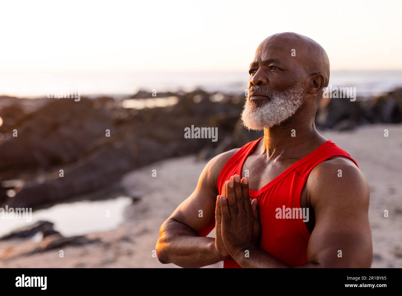 Fokussierter afroamerikanischer Senior-Mann, der Yoga praktiziert und am Strand posiert Stockfoto
