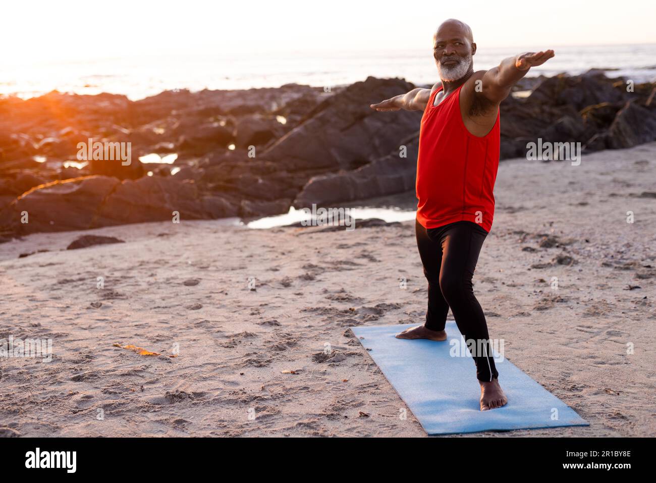 Fokussierter afroamerikanischer Senior-Mann, der Yoga praktiziert und am Strand posiert Stockfoto