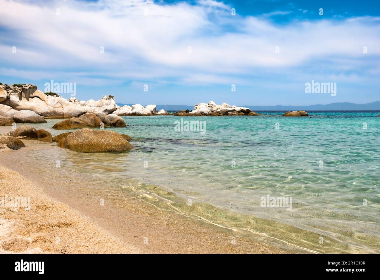 Breites Foto eines Sandstrands im Dorf Sarti in Griechenland. Der glatte und seidige Sand führt an einem wunderschönen sonnigen Tag in das smaragdgrüne Wasser. Stockfoto