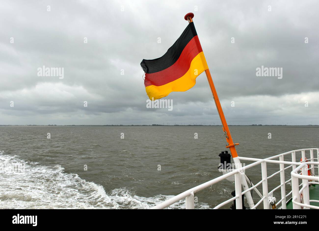 Die deutsche Flagge fliegt im Wind auf einer Fähre auf der Nordsee zwischen Bensersiel und Langeoog, Ostfriesische Inseln, Niedersachsen, Deutschland Stockfoto