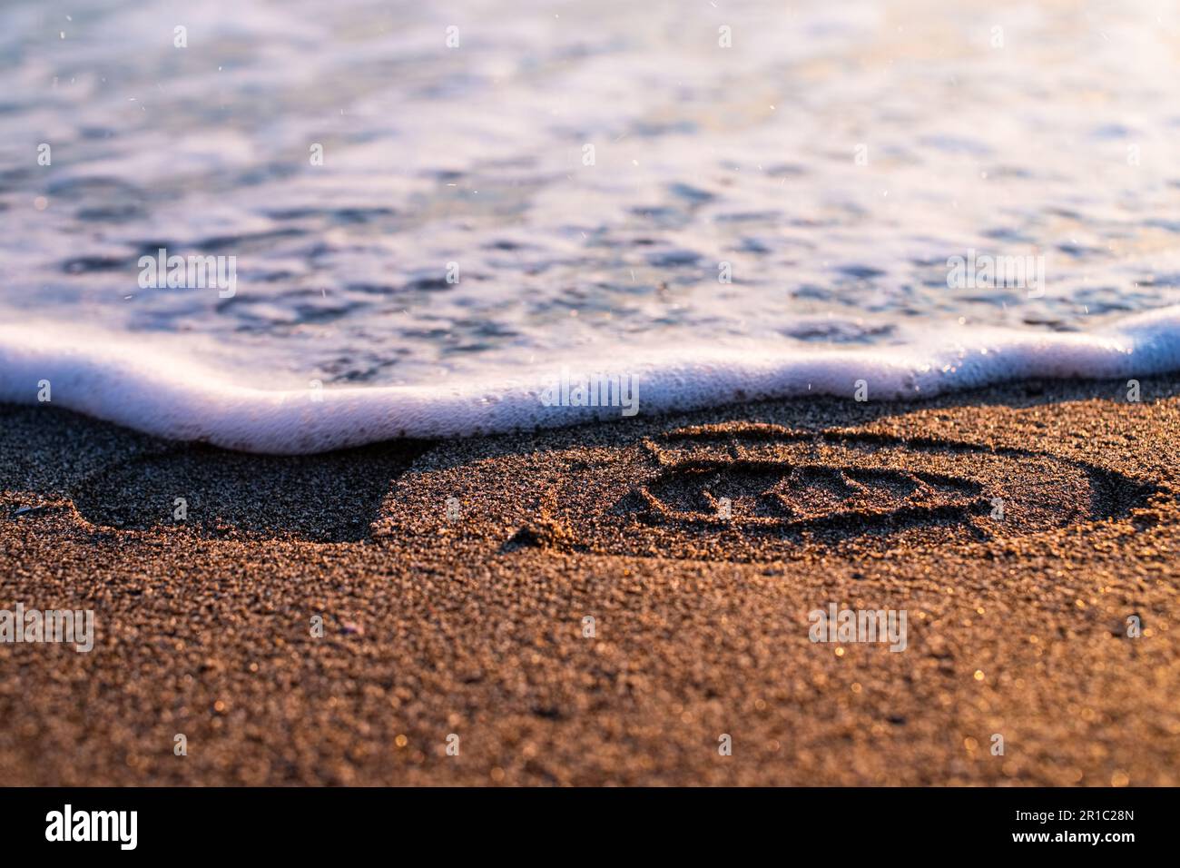 Sonnenuntergang am Strand. Schuhabdruck auf dem goldenen Sandstrand. Meerwasser wäscht einen Schuhabdruck. Mittelmeer, Marina Di Grosseto. Stockfoto