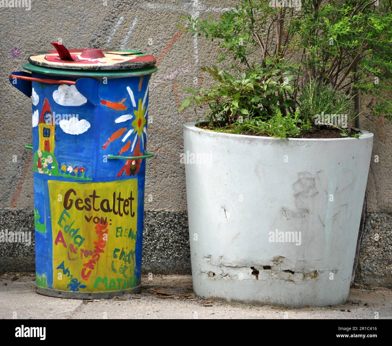 Alte, bemalte Mülltonnen können Seite an Seite mit einer Topfpflanze sein Stockfoto