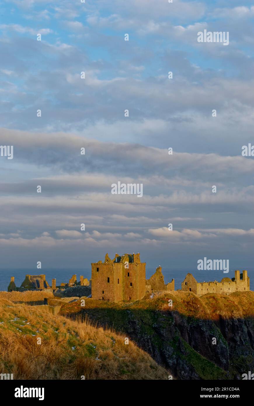 Dunnottar Castle in der Nähe von Stonehaven an der Ostküste Schottlands mit seinen zerstörten Gebäuden, die von der goldenen untergehenden Sonne erfasst wurden. Stockfoto