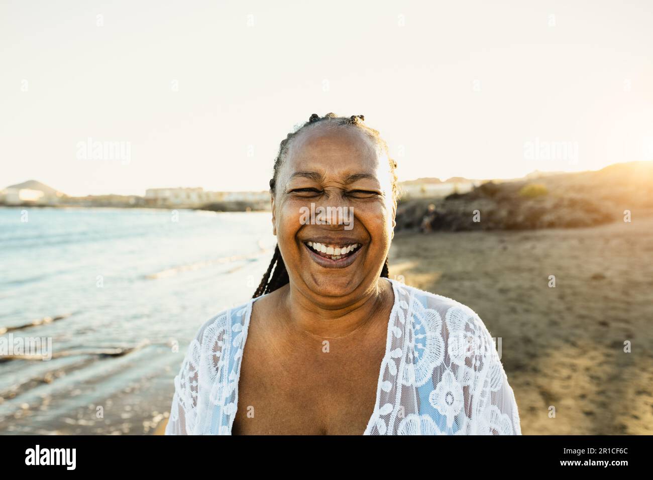 Glückliche afrikanische Seniorin, die während der Sommerferien am Strand in die Kamera lächelt - Lifestyle-Konzept für ältere Menschen Stockfoto
