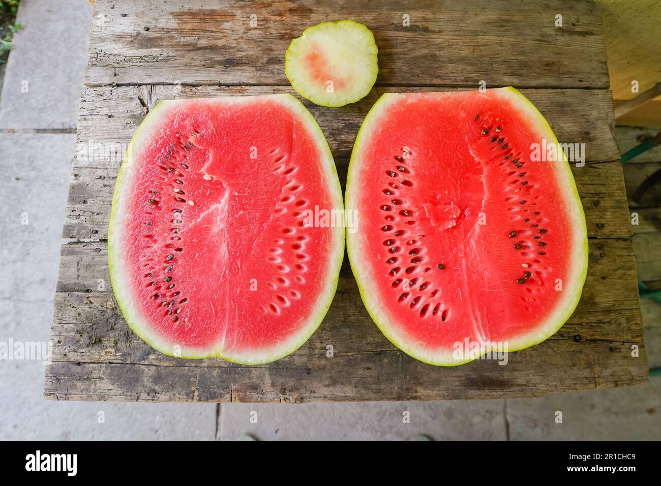 Lebhafte Wassermelone erfrischend geschnittene Hälfte auf Holztisch - Farm-to-Table Sommernack für gesunde Ernährung und saftiges nahrhaftes Festmahl Stockfoto