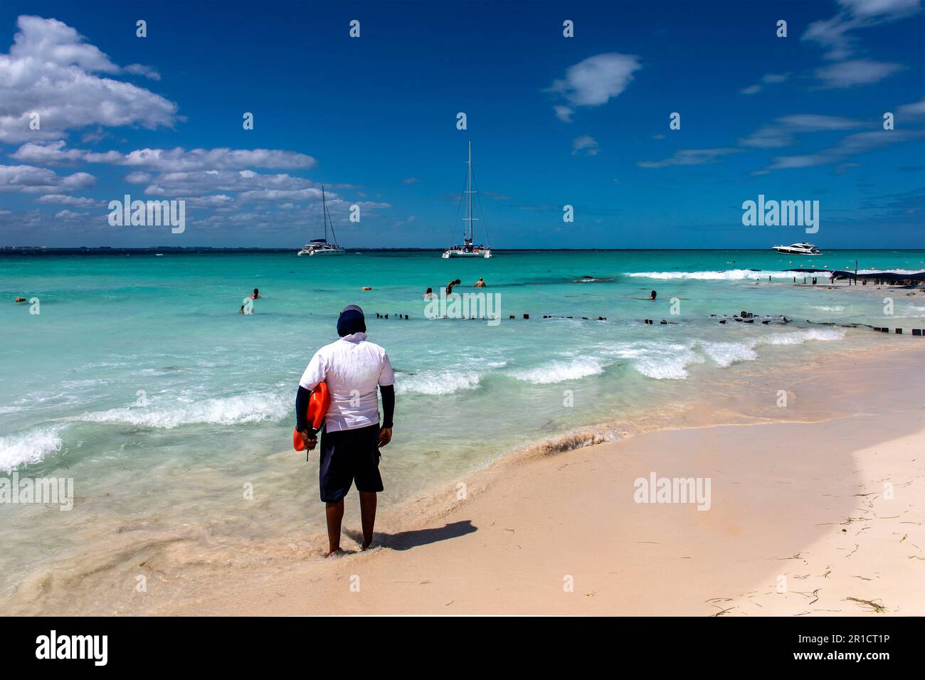 Strandschwimmer, der aufmerksam auf die Badegäste im türkisfarbenen mexikanischen Karibikwasser ist. Strandschwimmer am Strand von Inselfrauen in Mexiko. Stockfoto