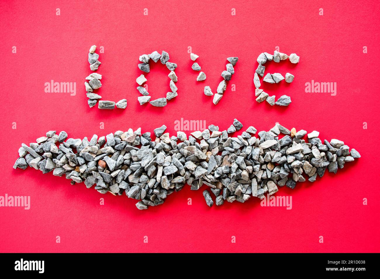 Die „LIEBE“-Buchstaben von vielen kleinen Steinen oder Kieseln sind das Konzept des Valentinstag oder Liebesfeiertags und werden auf einem roten Hintergrund platziert. Ich bin der Beste Stockfoto