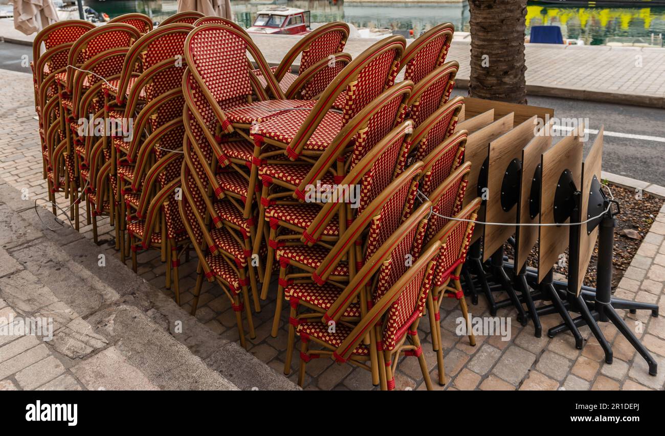 Stapel von Restaurantstühlen und Tischen auf einem Bürgersteig. Stockfoto