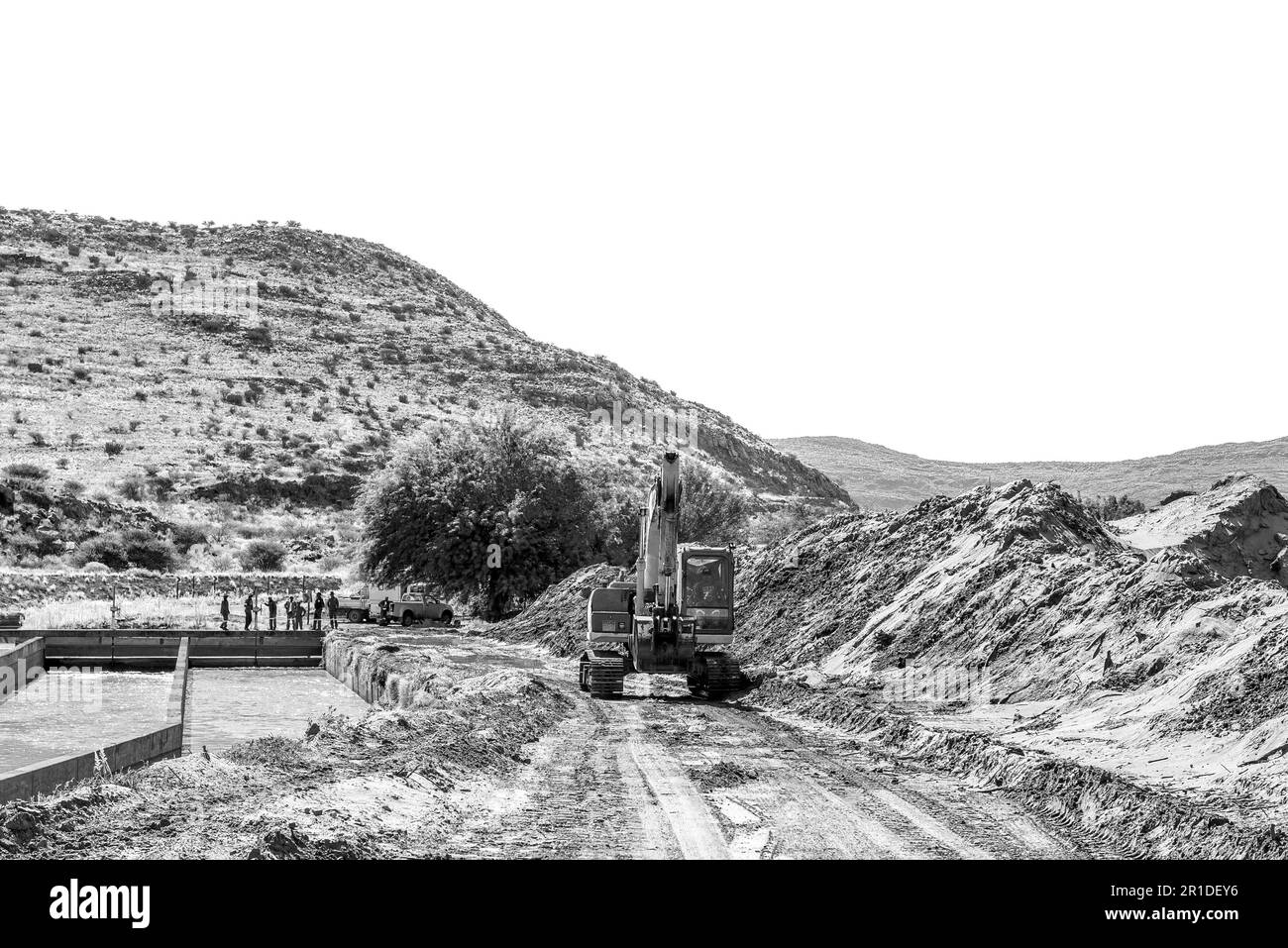Boegoeberg Dam, Südafrika - Februar 28 2023: Ein Baggerlader, der Sand reinigt, der den Bewässerungskanal in der Nähe des Boegoeberg Dams blockiert hat. Mitarbeiter sind sichtbar. Stockfoto
