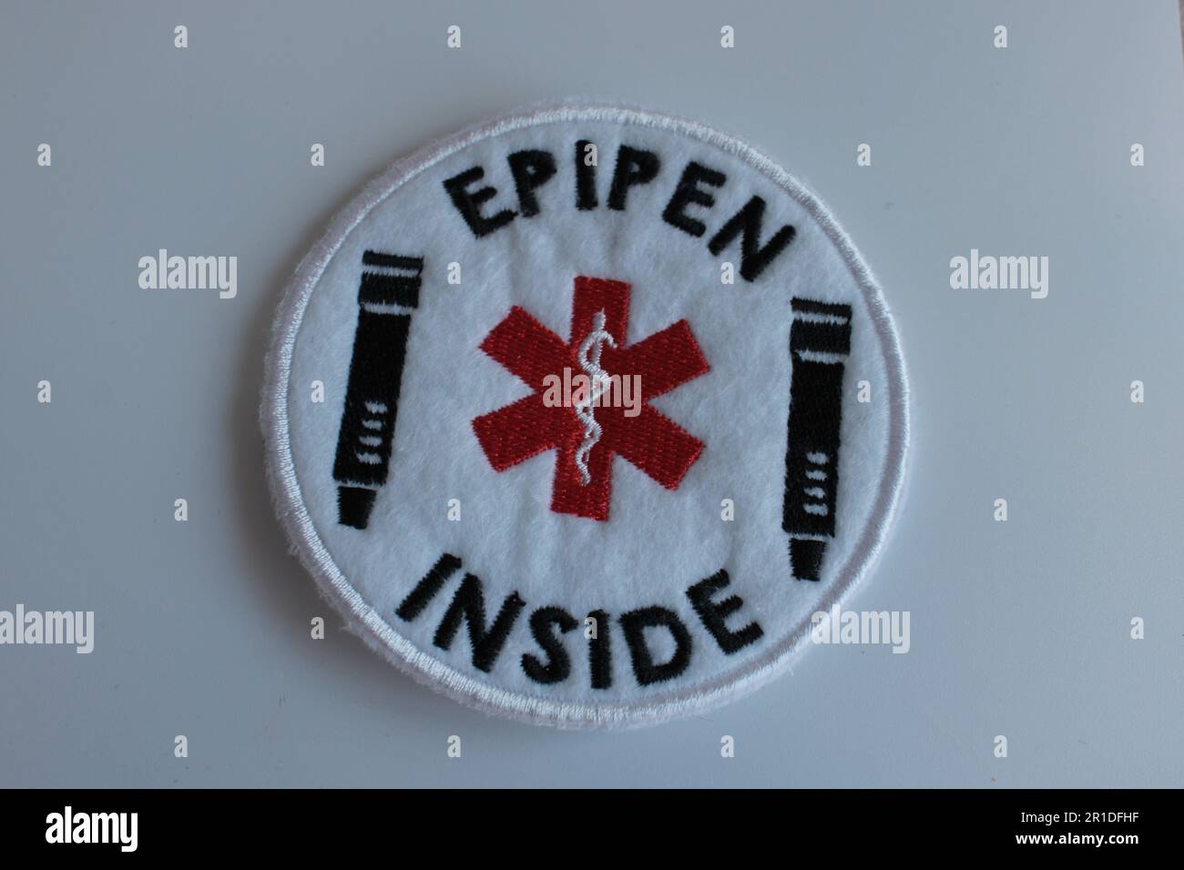 EpiPen Indisde Alarm bei anaphylaktischem Schock, nähen Sie das Pflaster auf einen einfachen Hintergrund. Lancashire, Vereinigtes Königreich, 13-05-2023 Stockfoto