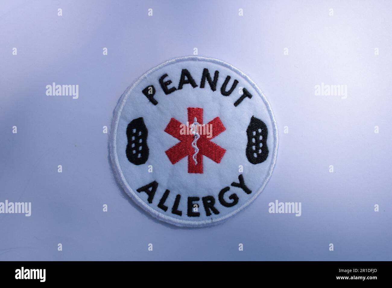 Erdnuss-Allergie-Alarm-Aufnäher auf einem einfarbigen Hintergrund mit Kopierbereich. Lancashire, Vereinigtes Königreich, 13-05-2023 Stockfoto